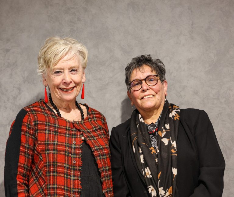 Two older women facing the camera and smiling.