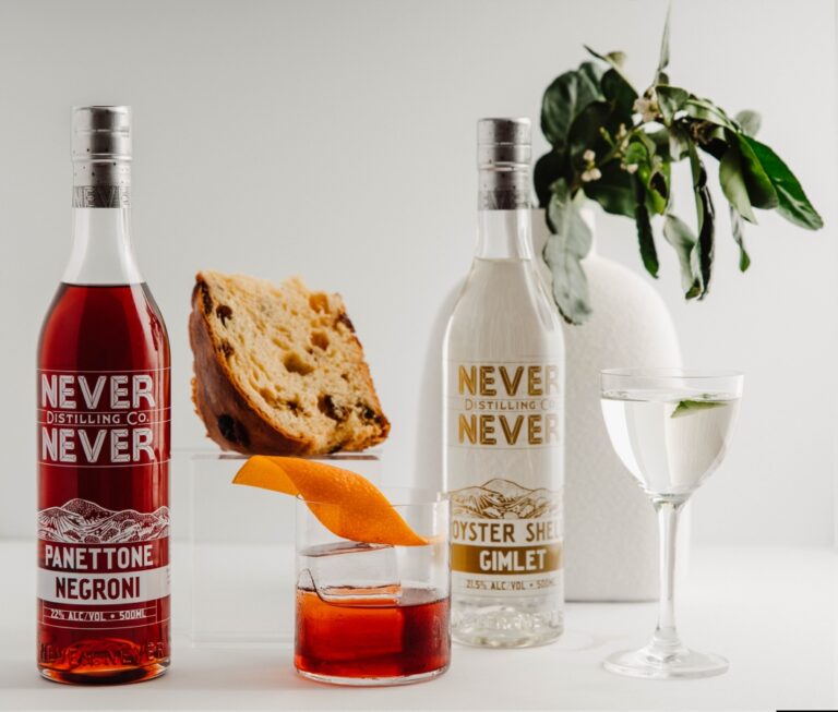 Two bottles of cocktails next to a low cocktail glass and a wine glass.