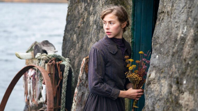 Woman holds wild flowers as she stands next to a door