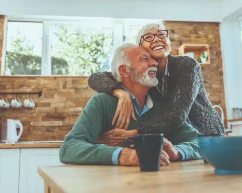 Older couple hugging in kitchen.