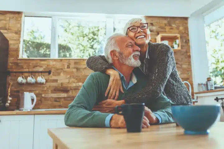 Older couple hugging in kitchen.