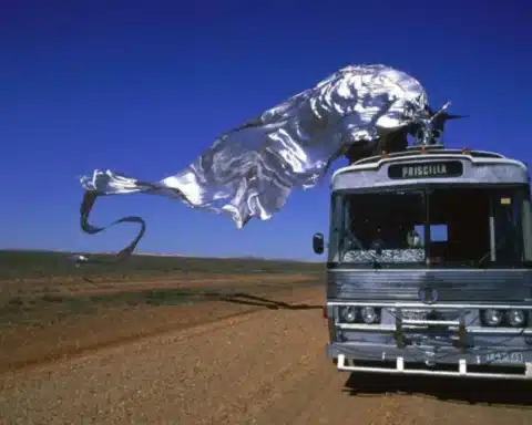 A bus featuring a large metal sculpture prominently displayed on its roof.