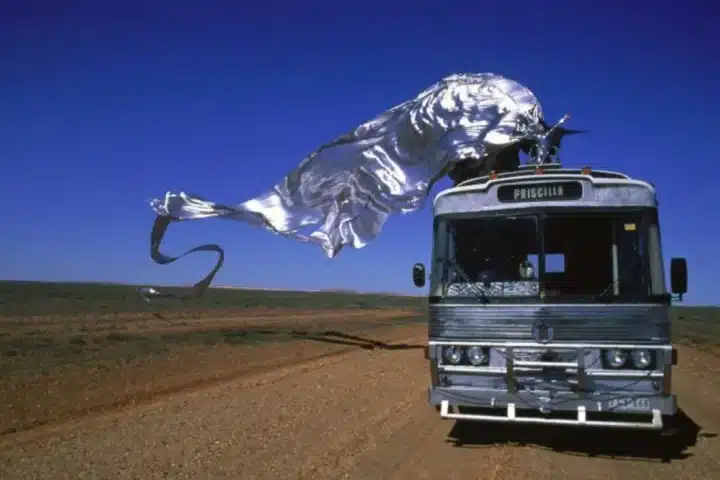 A bus featuring a large metal sculpture prominently displayed on its roof.