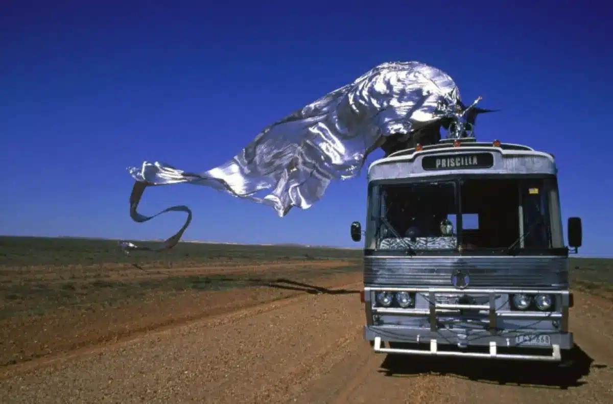 A bus featuring a large metal sculpture prominently displayed on its roof.