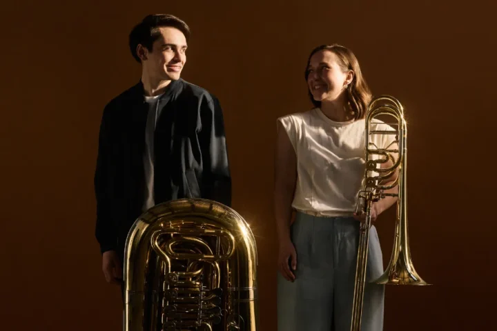 Musicians smile at each other while holding musical instruments.