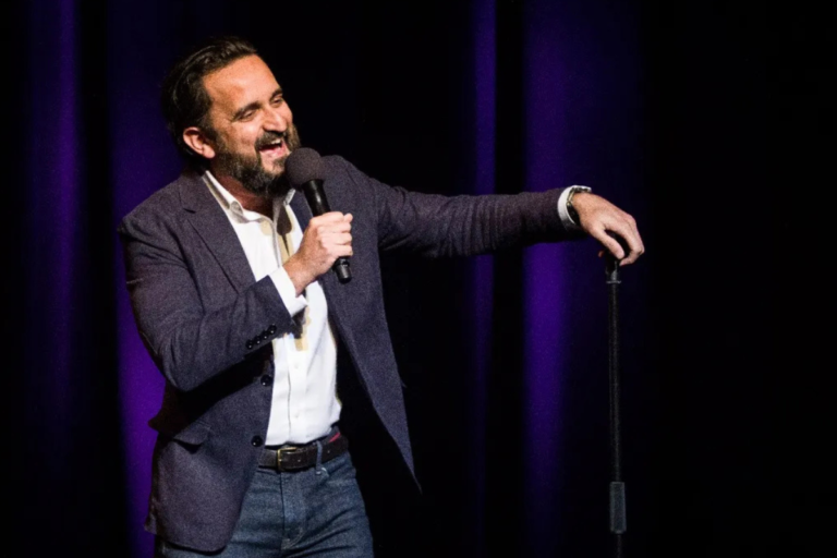 Comedian, Sami Shah on stage with microphone.