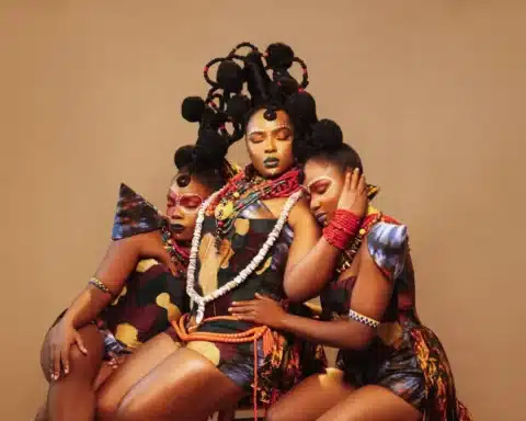 A trio of women dressed in colorful attire, happily posing for a group photograph.