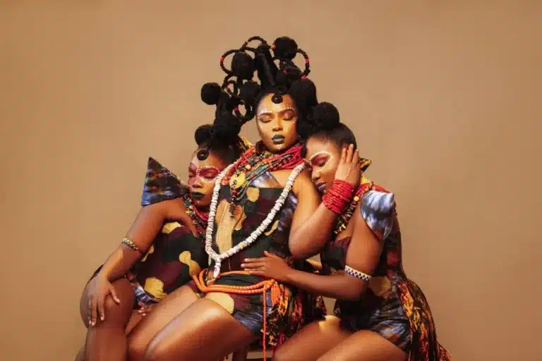 A trio of women dressed in colorful attire, happily posing for a group photograph.