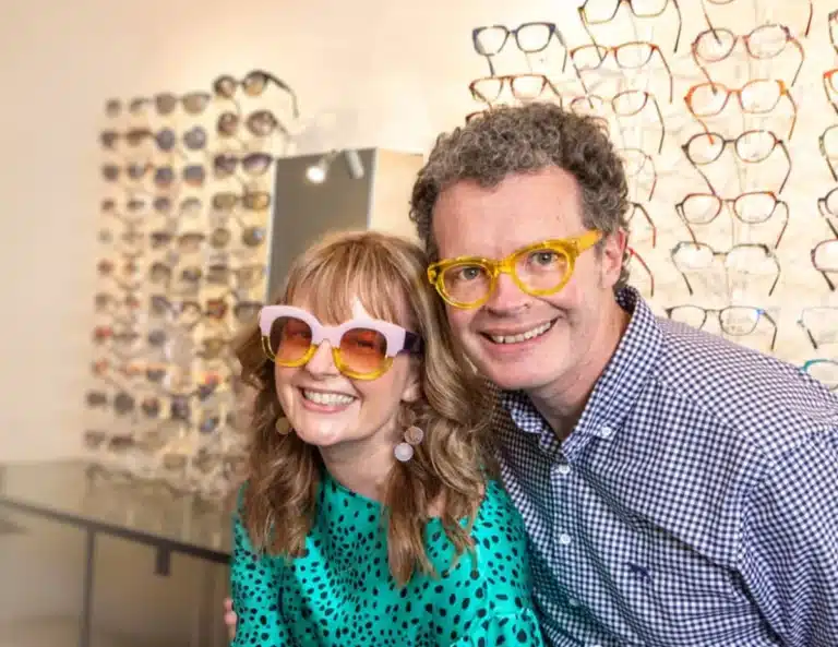 In a store, a man and woman with glasses are seen together, actively shopping and reviewing items on display.