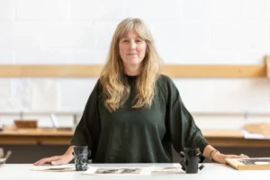 Woman smiles at the camera at work bench.