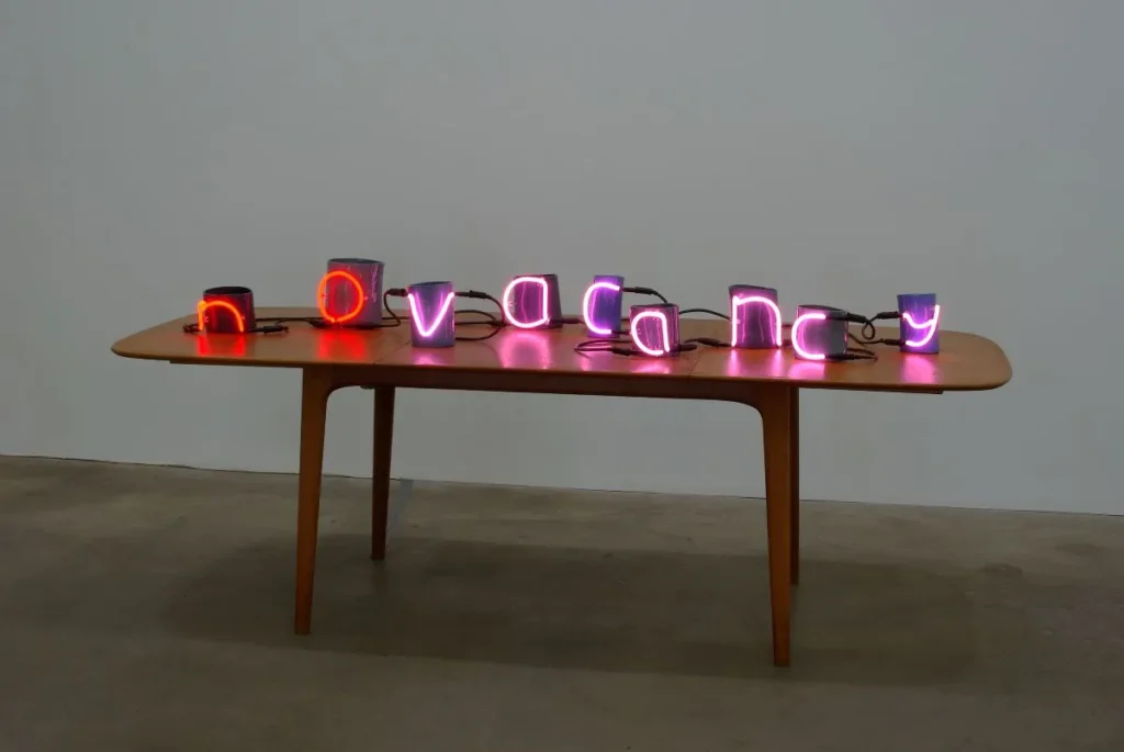 Neon lights reading 'No Vacancy' sits on a wooden table.