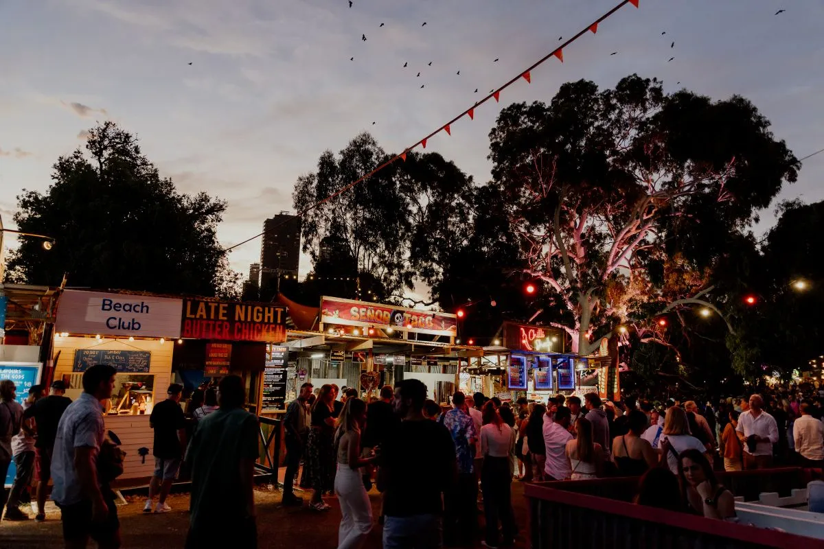 A bustling outdoor food market filled with a diverse crowd enjoying various food stalls and vibrant atmosphere.