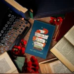 A typewriter, stacked books, and a bouquet of flowers elegantly arranged on a wooden table.