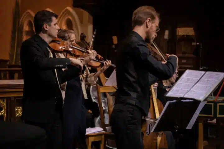 A group of musicians performing together inside a church, creating a harmonious atmosphere with their instruments.