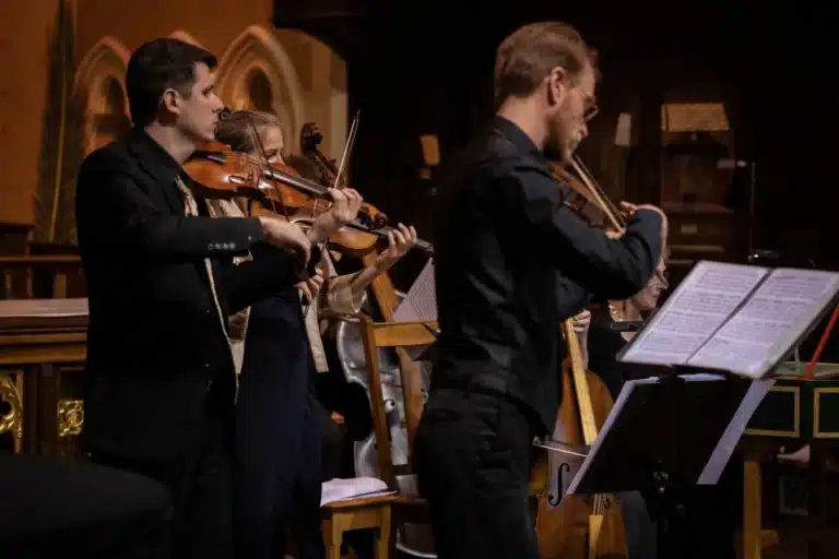 A group of musicians performing together inside a church, creating a harmonious atmosphere with their instruments.