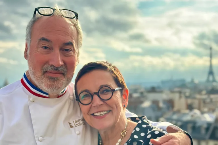 A man and woman pose together in front of the Eiffel Tower.