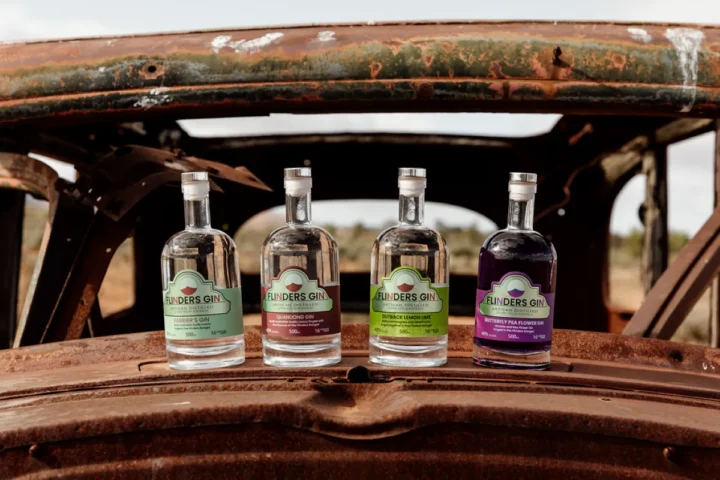 Four bottles of alcohol arranged on the back of a vintage car, showcasing a rustic and nostalgic vibe.