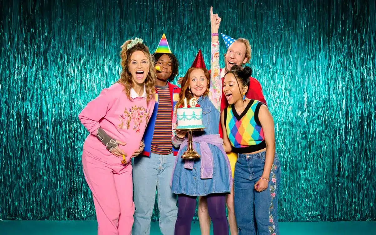 A group of smiling people gathered around a birthday cake, celebrating with joy in a festive atmosphere.