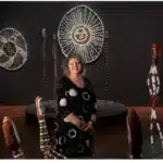 A woman stands in front of a vibrant display showcasing various pieces of native art.