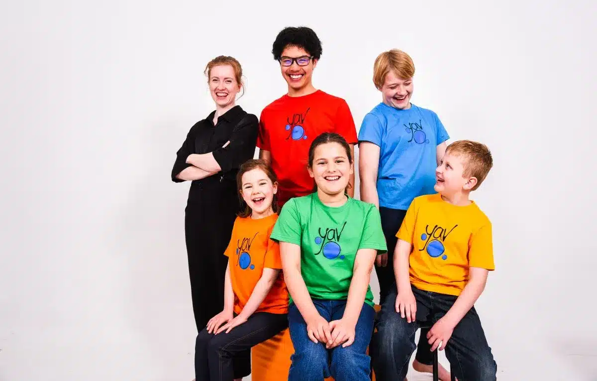 A group of smiling children in bright, colorful shirts posing together for a cheerful photo.