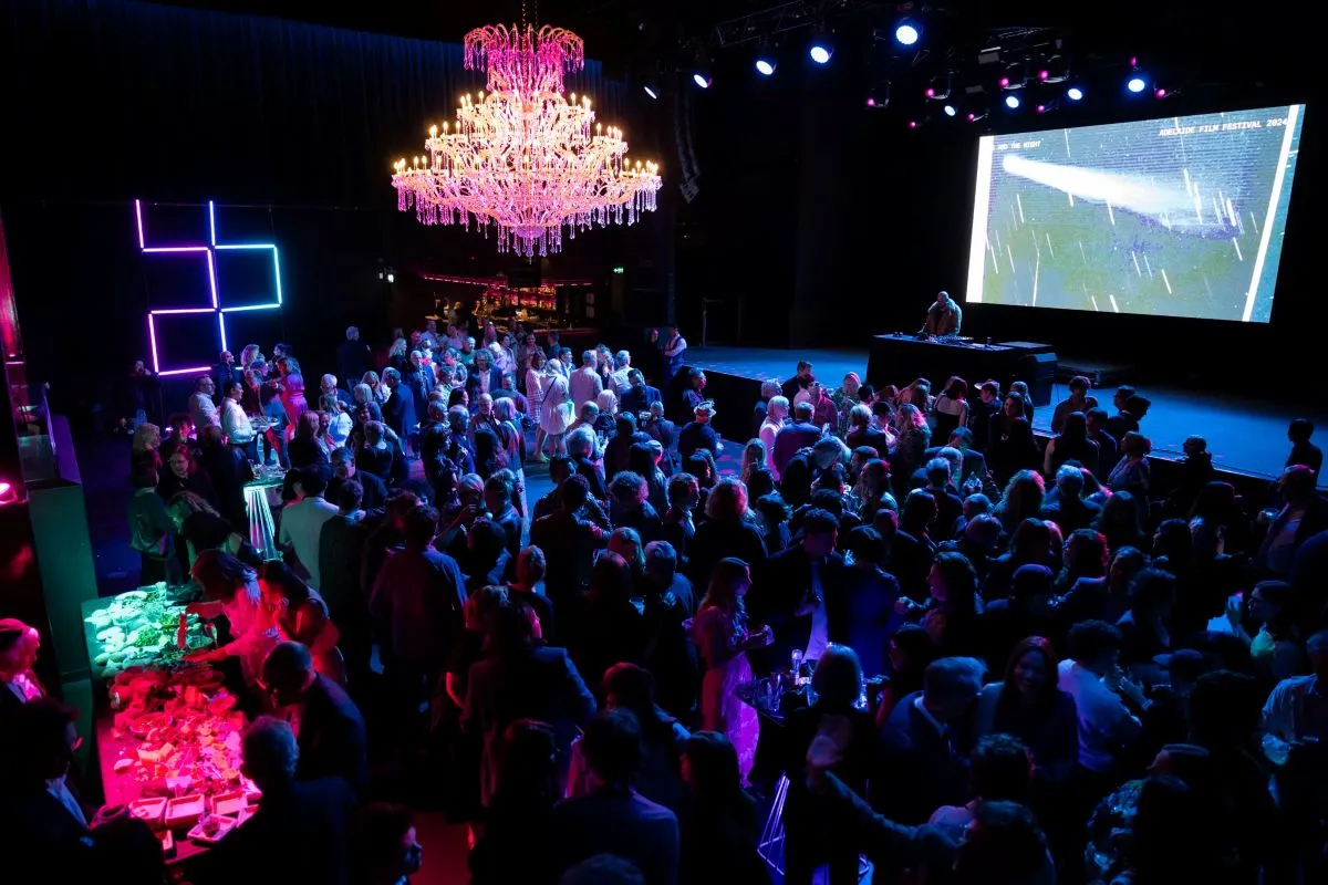 A vibrant crowd gathered in a room illuminated by colorful neon lights, creating an energetic atmosphere.