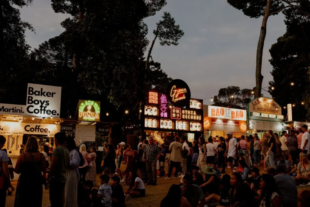 A bustling crowd enjoying various food stalls at a lively food fair, filled with diverse people and vibrant colors.