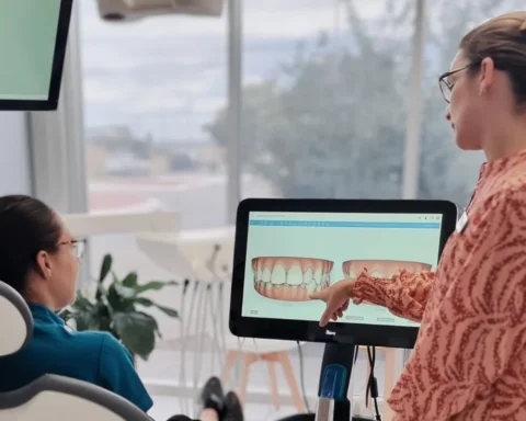 A woman demonstrates something on a computer to a patient in a medical office setting.