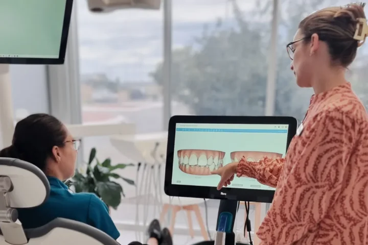 A woman demonstrates something on a computer to a patient in a medical office setting.