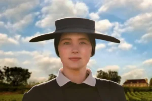 A woman in a black hat and black dress stands confidently, exuding elegance and style.