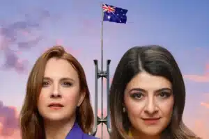 Two women stand beside a flagpole displaying the Australian flag, smiling and enjoying the outdoors.