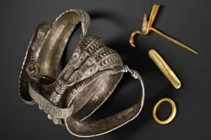 A pair of gold earrings, a gold ring, and a gold bracelet displayed elegantly on a soft fabric background.