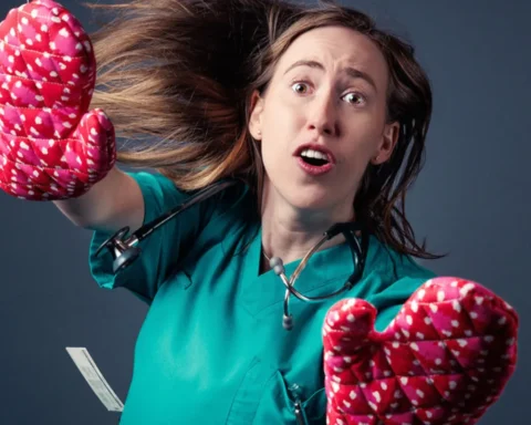 A woman in a green scrub suit is holding two oven mitts, ready to handle hot dishes with care and safety.