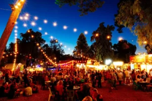 A vibrant food festival scene featuring a large crowd enjoying various culinary delights and socializing together.