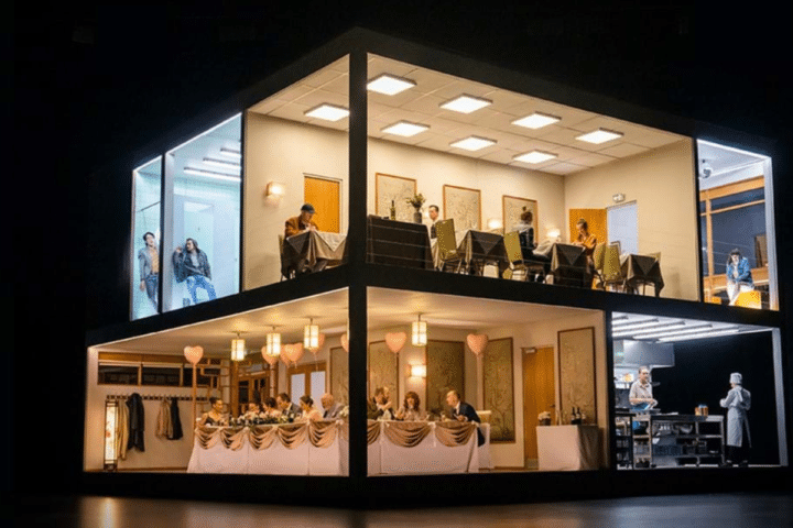 A model house with people gathered around tables, enjoying a social gathering in a cozy setting.