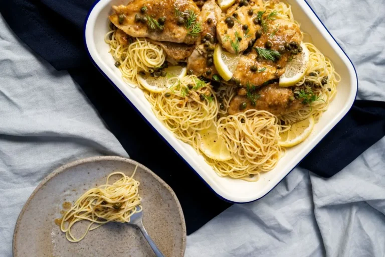 A plate of chicken and noodles garnished with fresh lemon slices.