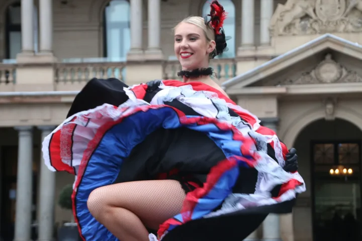 A woman dances joyfully in a vibrant red, white, and blue dress.