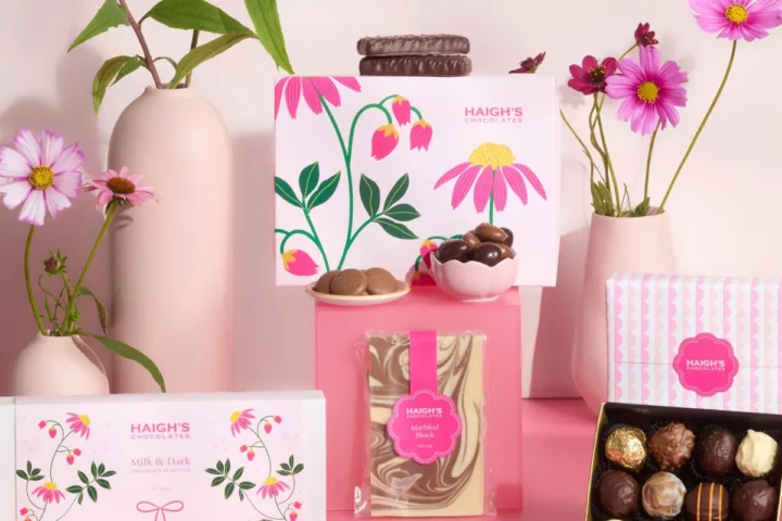 A pink box filled with assorted chocolates and vibrant flowers, creating a cheerful and festive display.